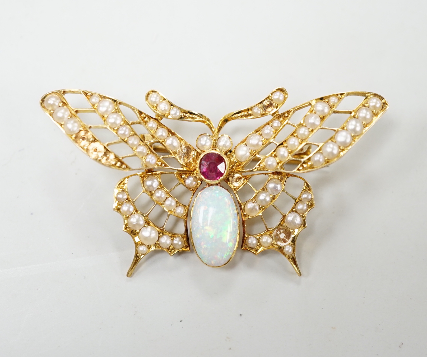 A yellow metal ruby, white opal and seed pearl cluster set bug brooch, width 48mm, gross weight 7 grams